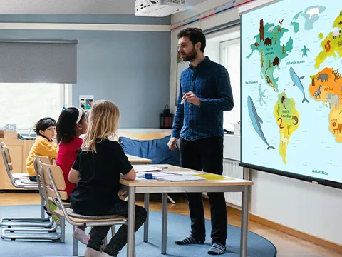 Teacher standing in front of a classroom using a projector to teach