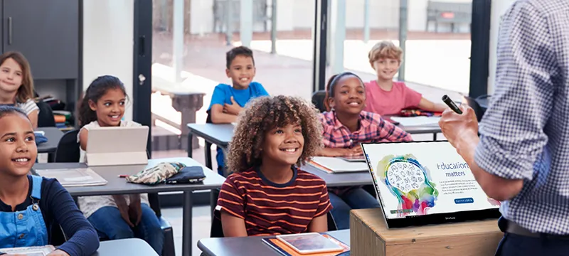 Teacher using a portable monitor to view content while teaching a room of students