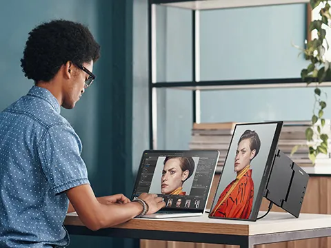 Man color editing using a laptop and portable monitor