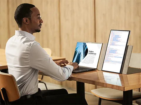 Man working at a desk using a laptop and portable monitor