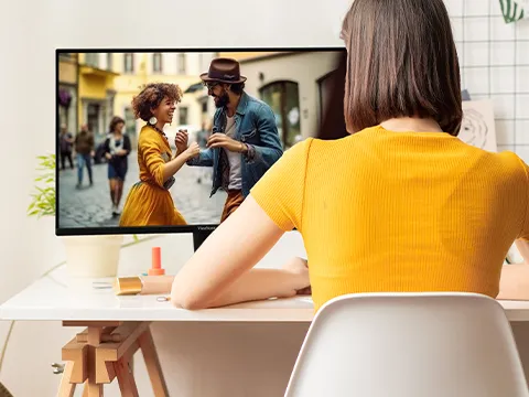 Woman sitting at desk watching a movie on her monitor