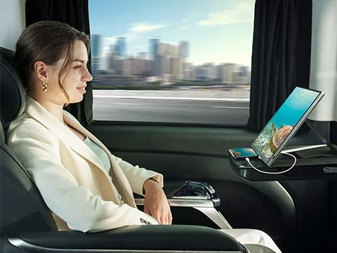 a woman on a train with a phone connected to a portable monitor
